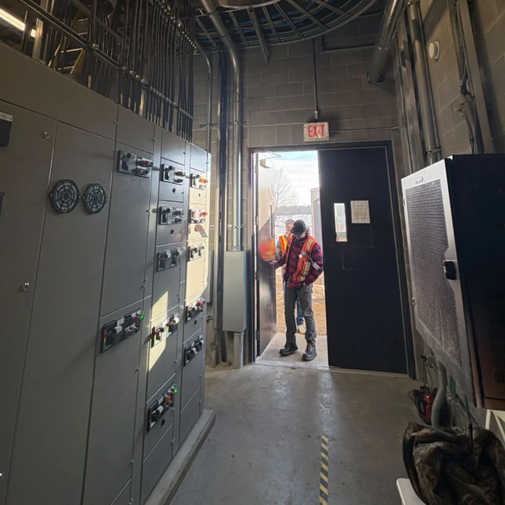 Technician entering electrical infrastructure room with switchgear systems in Alberta